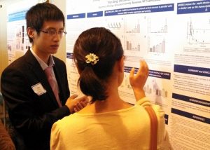 Two students discussing research results in front of a poster.